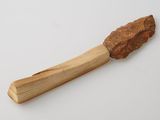 une cuillère en bois avec un manche en bois posée sur une surface blanche