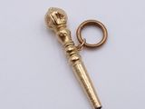 a gold keychain that has a microphone on it