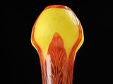 a glass vase that has a yellow and red design on it