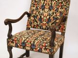 une vieille chaise avec un dossier et des accoudoirs tapissés de fleurs