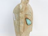 beige ceramic sculpture of a woman ' s face with a turquoise stone in her eye