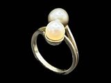 two white pearls are set in a gold ring on a black background