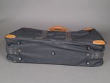 a black suitcase with a brown handle on a gray surface