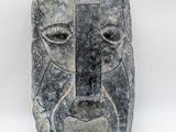 a stone sculpture of a face on a white background