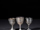 three silver goblets sitting on a table with a black background