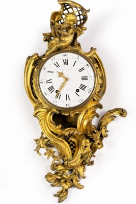 une horloge en or accrochée au mur, surmontée d'une couronne