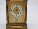 a small gold clock with a key on a white background