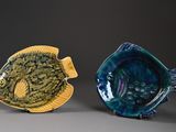 two ceramic fish sitting next to each other on a table