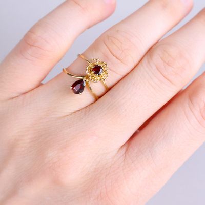 Quelqu'un tient une bague en or sertie d'un grenat.