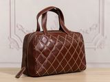 brown quilted leather handbag on a wooden table with a white wall in the background