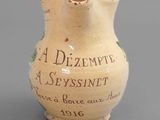un petit vase orné d'une inscription, posé sur une table