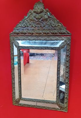 un miroir accroché à un mur rouge, avec une chaise rouge en arrière-plan