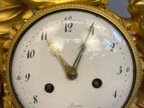 a gold clock with a statue of a man and a woman on it