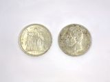 two silver coins sitting next to each other on a white surface