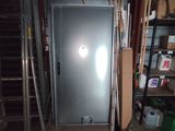 une porte métallique dans une pièce équipée d'étagères et d'une échelle