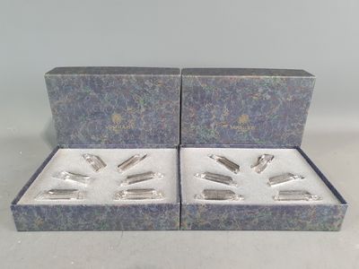 trois objets plaqués argent dans une boîte bleue posée sur une table