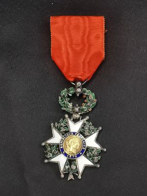 un gros plan d'une médaille posée sur une surface noire, avec un ruban rouge