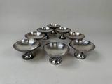 six silver plated candlesticks in a circle on a white surface