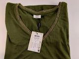 a green t - shirt with a tag on it sitting on a white surface