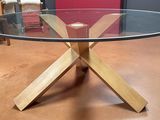une table en verre avec des pieds en bois et un plateau en verre
