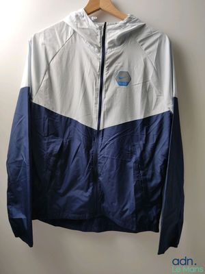 une veste blanche et bleue accrochée au mur à côté d'un cintre en bois