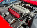 a red car with a red engine and a black hood