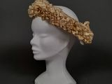 une tête de mannequin blanche coiffée d'un chapeau à fleurs