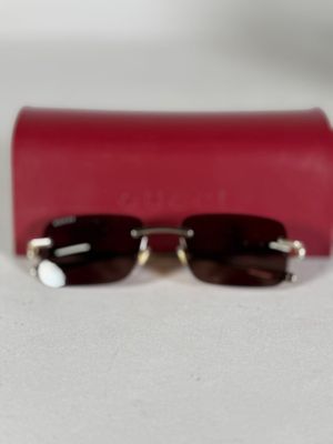 une paire de lunettes de soleil et un étui rouge posés sur une surface blanche