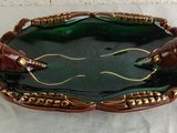 a green and gold crab shaped dish on a white cloth