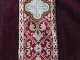 a close up of a red and gold tie with a cross on it