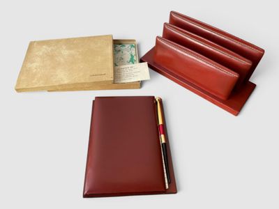 un portefeuille en cuir rouge contenant un stylo, un bloc-notes et un porte-stylo