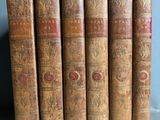 six vieux livres sont alignés les uns à côté des autres sur une étagère