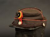 a brown hat with a red ribbon and a button on it