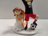 a figurine of a bride and groom with a soccer ball