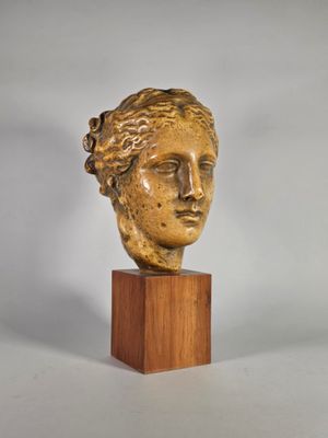 un gros plan d'une sculpture représentant une tête de femme posée sur un socle en bois