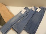 three pairs of jeans sitting on top of a table next to each other