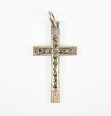 un gros plan d'une croix argentée sur fond blanc