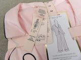 a pink shirt with a label on it and a pair of scissors