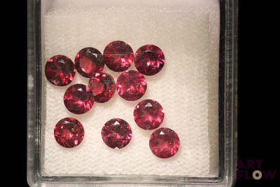 des tourmalines roses dans un récipient en verre posé sur une surface blanche