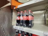 many bottles of coke on the shelves in the store
