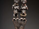une statue en bronze représentant deux personnages debout au sommet d'un vase