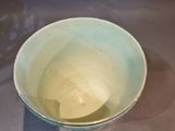 a blue bowl sitting on a table with a shadow of a person