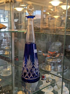 une vitrine en verre sur laquelle est posé un vase bleu