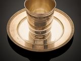 a silver cup and saucer on a black table