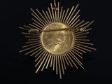 a close up of a gold coin with a sunburst on it
