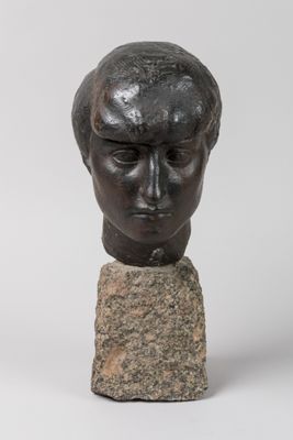 a bronze head of a man on a rock