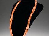 an orange beaded necklace on a black mannequin