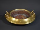 a gold plate with a handle on a black background