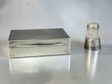 a small silver thimble next to a small silver thimble