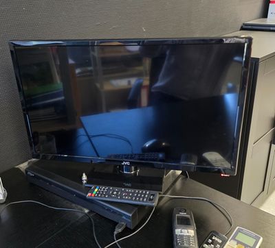 un téléviseur à écran plat posé sur un bureau, à côté d'une télécommande